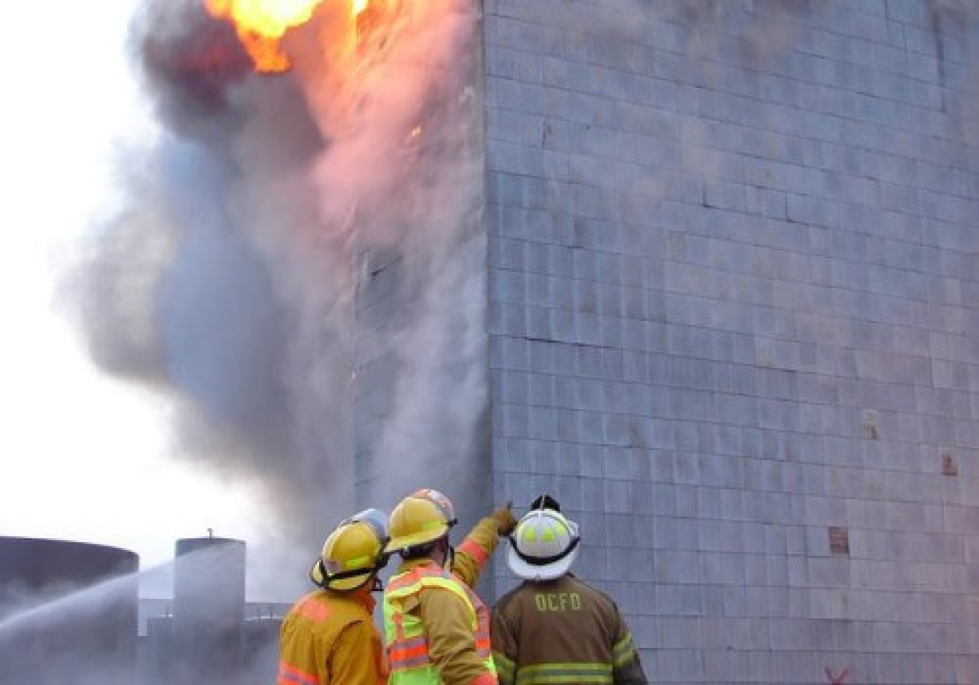 Image of firefighters pointing at a building on a fire after an emergency or natural disaster.